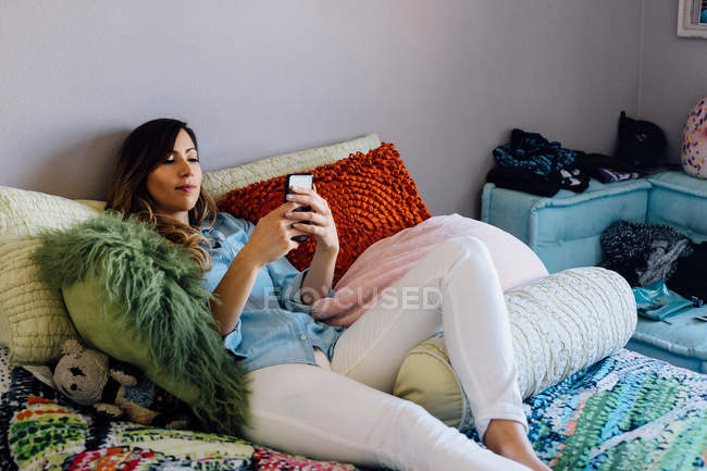 Junge Frau auf schäbig schickem Bett — Stockfoto
