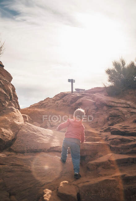 Chico joven escalando roca en el desierto, vista trasera, Moab, Utah, EE.UU. - foto de stock