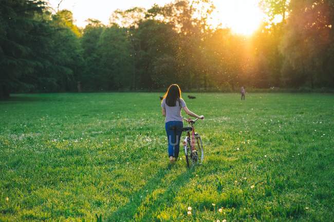 Donna a piedi bicicletta su erba — Foto stock