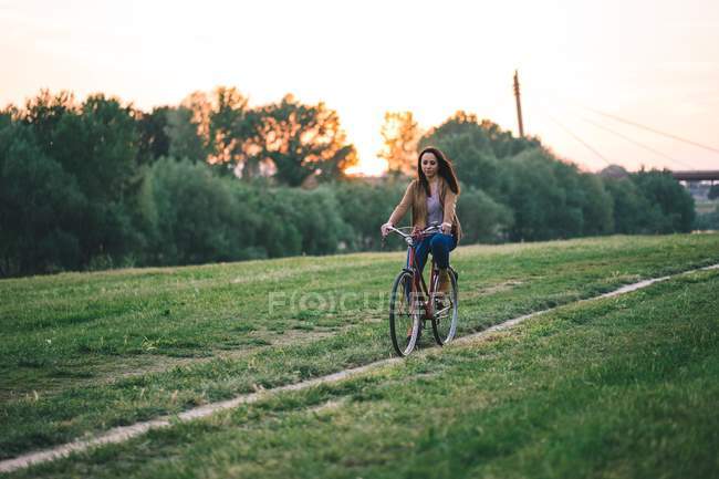 Woman riding bicycle on grass — Stock Photo