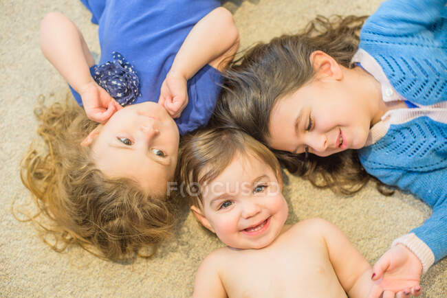 Hermanas tumbadas en el suelo - foto de stock