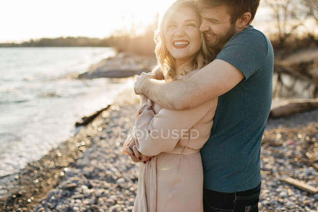 Pareja junto al lago, hombre abrazando a la mujer - foto de stock