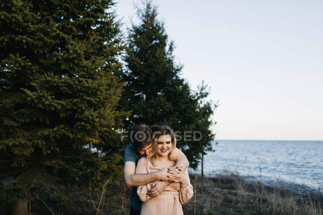 Coppia accanto all'acqua, uomo che abbraccia donna — Foto stock