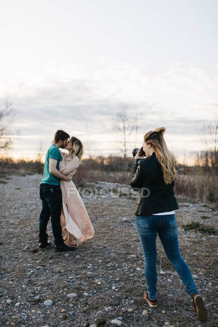 Fotógrafo fotografando casal, casal beijando em ambiente rural — Fotografia de Stock