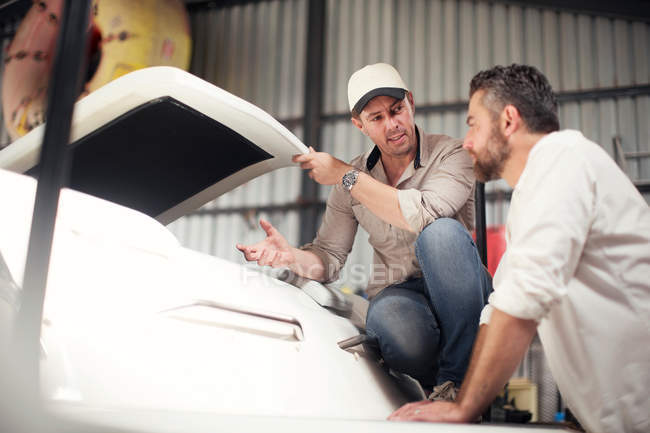 Deux hommes vérifient la carrosserie du bateau en atelier de réparation — Photo de stock