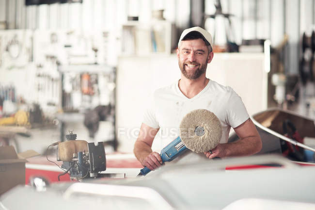 Portrait of man with polishing machine in boat repair workshop — Stock Photo