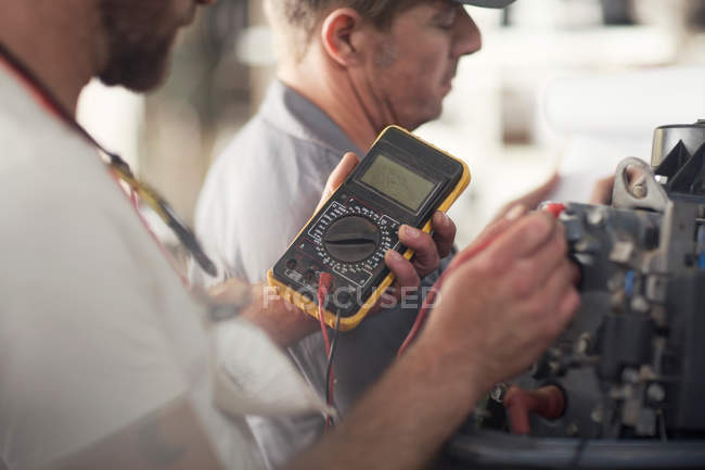 Чоловік використовує машину для тестування бортового двигуна в майстерні ремонту човнів — стокове фото