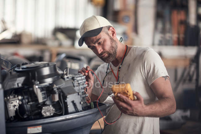 Man using machine to test outboard motor in boat repair workshop — Stock Photo