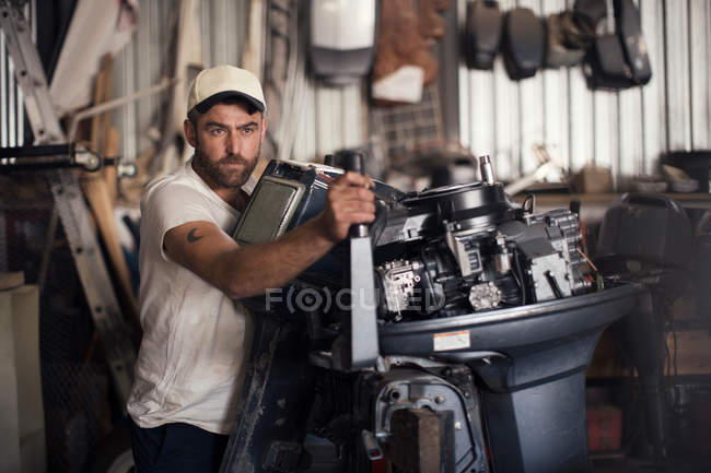 Man testing outboard motor in boat repair workshop — Stock Photo
