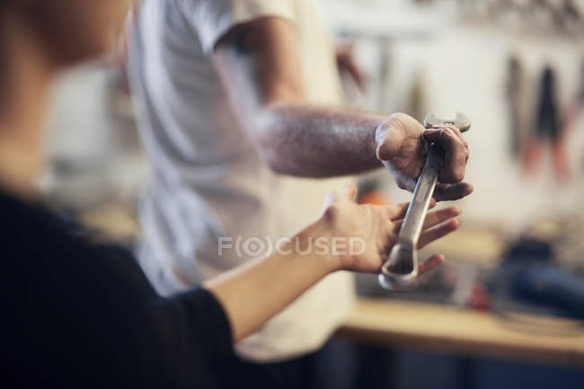 Men handing wrench in boat repair workshop — Stock Photo