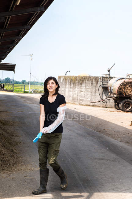 Female farmer putting on protective glove — Stock Photo