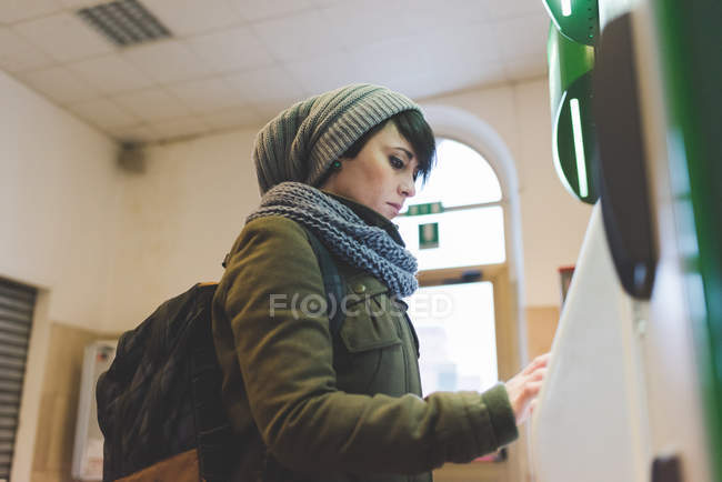 Femme en bonnet tricoté à l'aide d'un écran tactile — Photo de stock