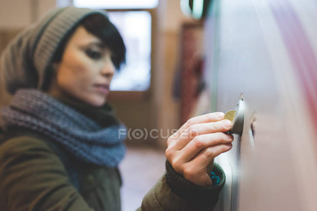 Mujer en punto sombrero insertar moneda - foto de stock