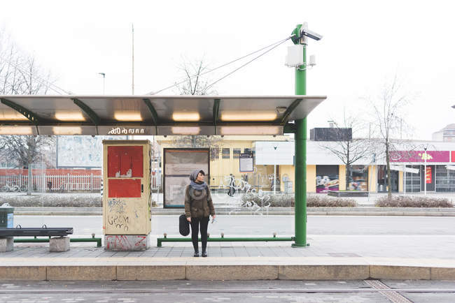 Female backpacker standing at bus station — Stock Photo