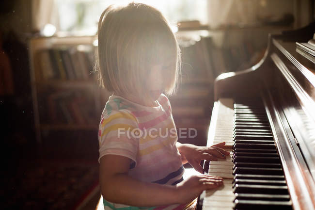 Chica tocando piano viejo - foto de stock