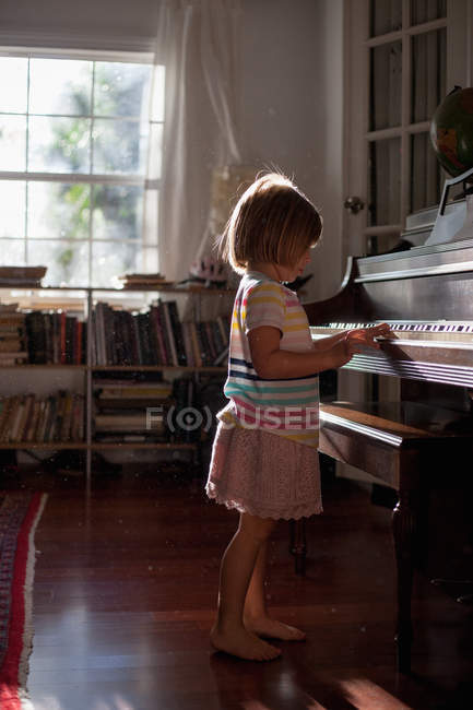 Дівчина стоїть і грає на піаніно — стокове фото