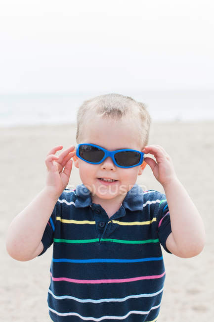Toddler putting on blue sunglasses — Stock Photo