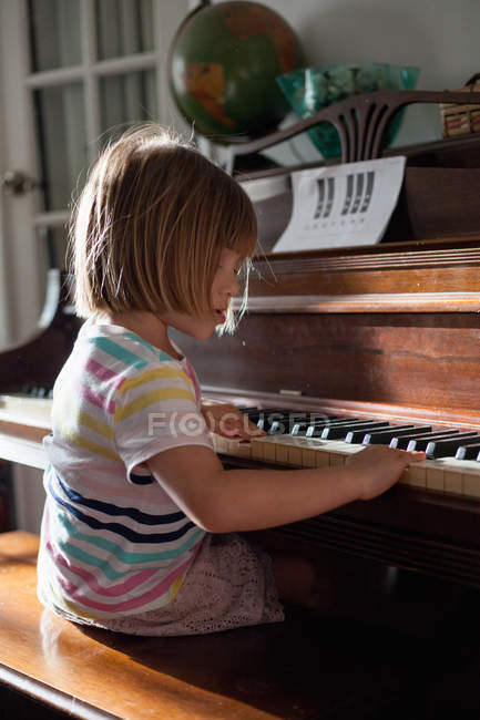 Girl sitting and playing piano — Stock Photo