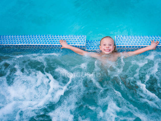 Bonito menino salpicando na piscina — Fotografia de Stock