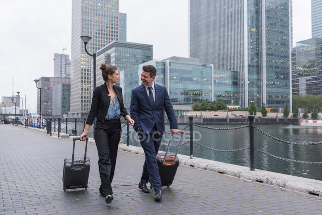 Бізнесмен і бізнес-леді тягнуть багажник — стокове фото