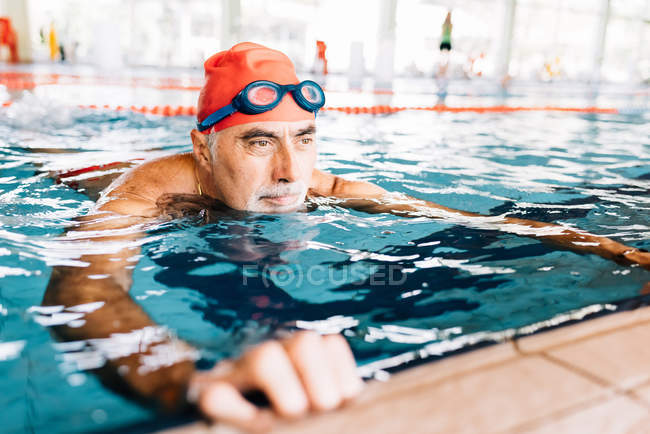 Homme relaxant dans l'eau au bord de la piscine — Photo de stock