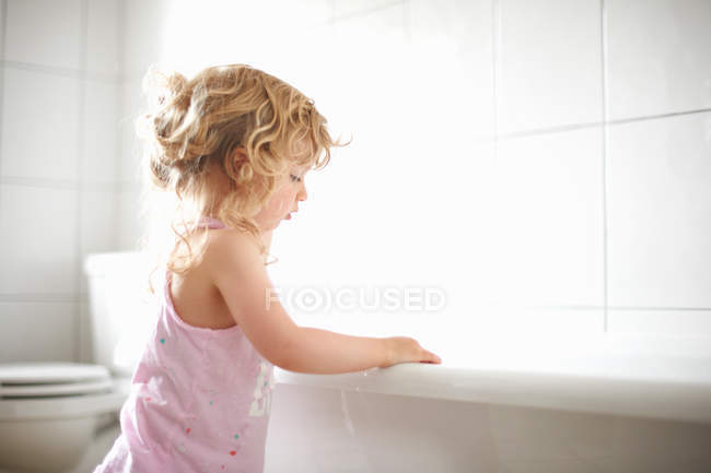 Chica de pie al lado de la bañera - foto de stock