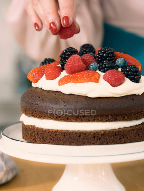 Mulher decorando bolo de chocolate — Fotografia de Stock