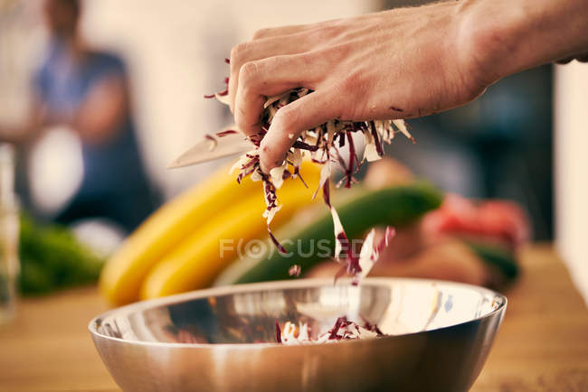 Шеф-повар кладет нарезанные листья салата — стоковое фото
