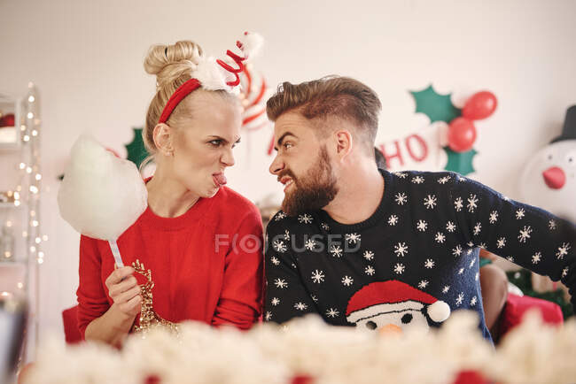 Joven hombre y mujer haciendo caras el uno al otro en la fiesta de Navidad - foto de stock