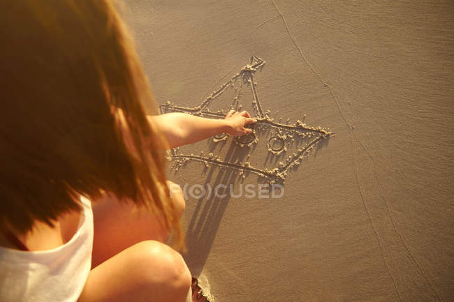 Giovane donna disegno in sabbia — Foto stock