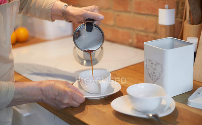 Mujer vertiendo café en tazas - foto de stock