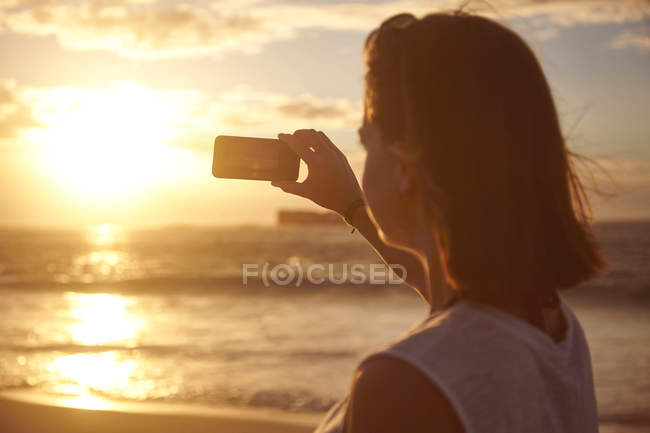 Jovem mulher na praia, fotografando vista — Fotografia de Stock
