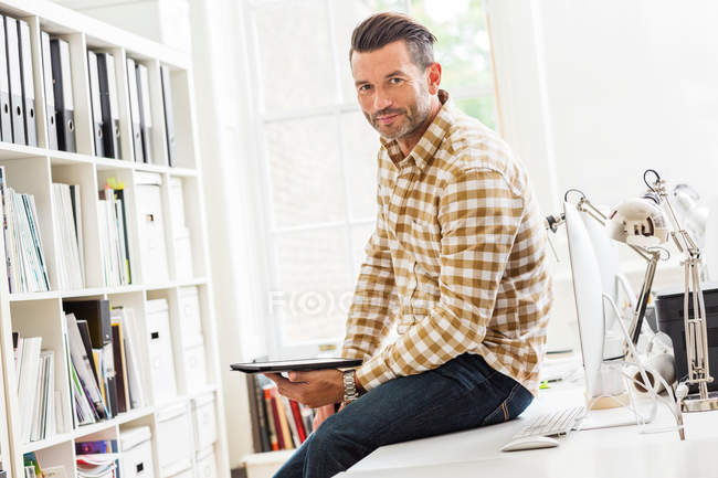 Male designer sitting on desk — Stock Photo