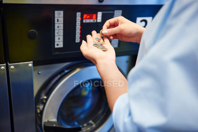 Woman selecting coins for washing machine — Stock Photo