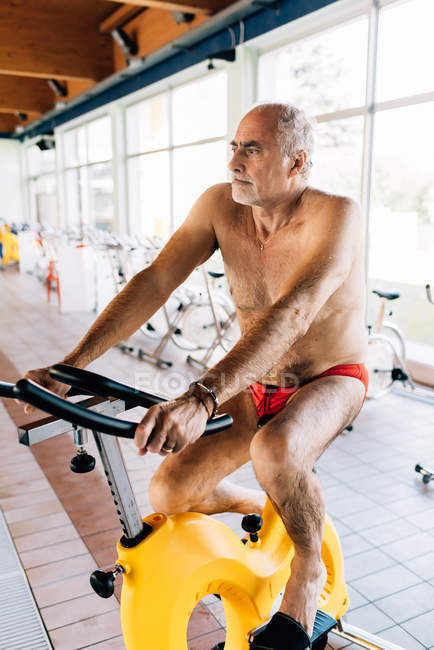 Людина на фізичному велосипеді в тренажерному залі — стокове фото