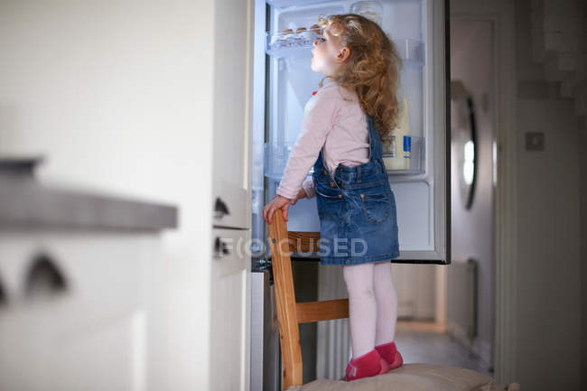 Young girl standing on chair — Stock Photo