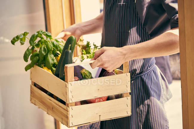 Chef portant une caisse de légumes — Photo de stock