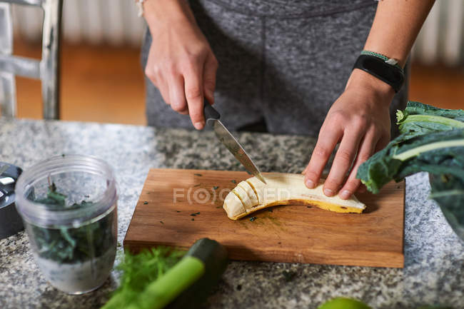Jovem mulher cortando banana — Fotografia de Stock