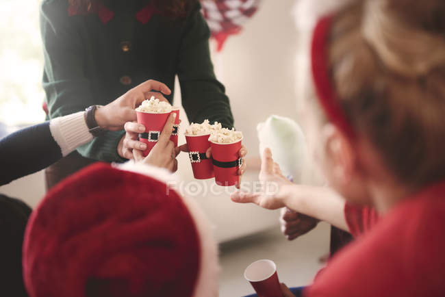 Cropped shot of young woman handing out popcorn at christmas party — Stock Photo