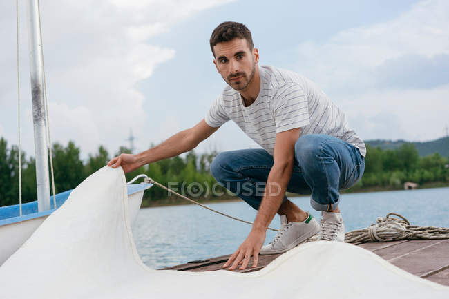 Young man folding boats sail — Stock Photo