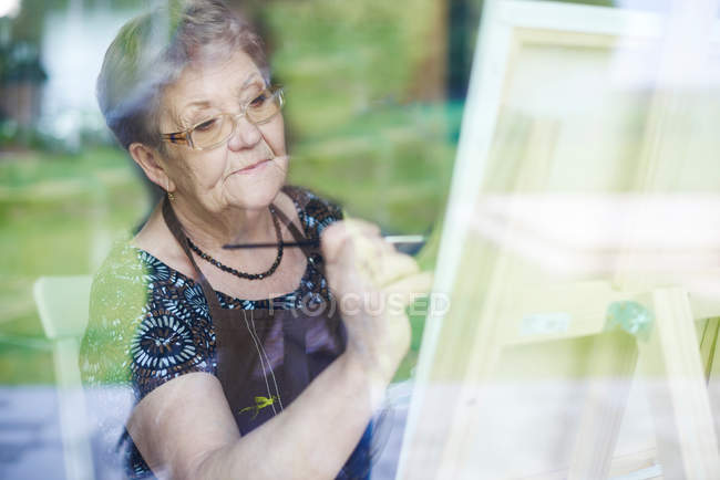 Woman painting on easel — Stock Photo
