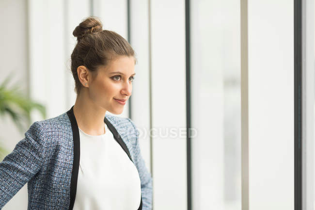 Aufsässige Geschäftsfrau blickt durchs Fenster — Stockfoto