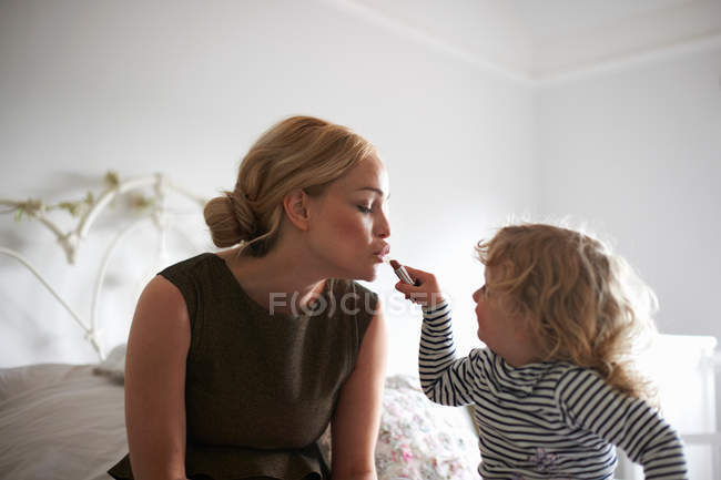 Daughter helping mother put on lipstick — Stock Photo