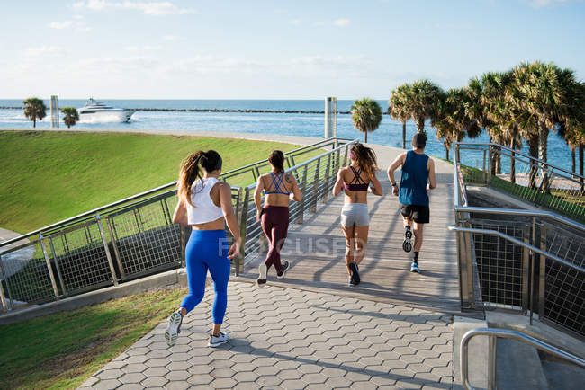 Three women running with personal trainer — Stock Photo