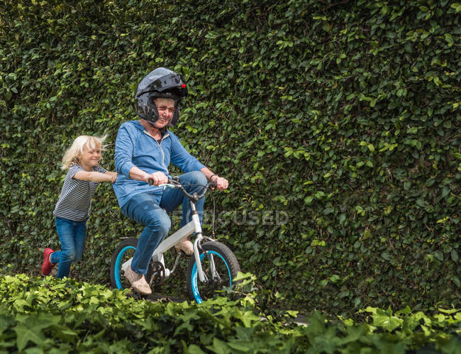 Внук толкает бабушку на велосипед. — стоковое фото