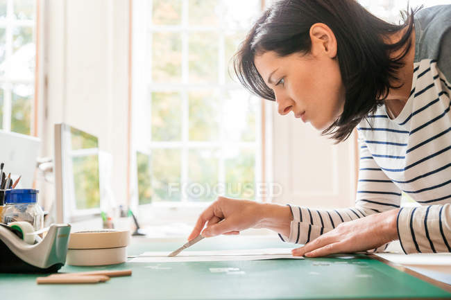 Female designer cutting paper — Stock Photo