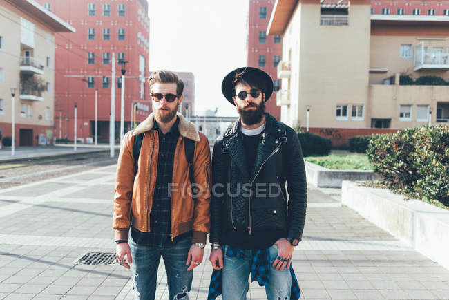 Hipster friends standing in city housing estate — Stock Photo