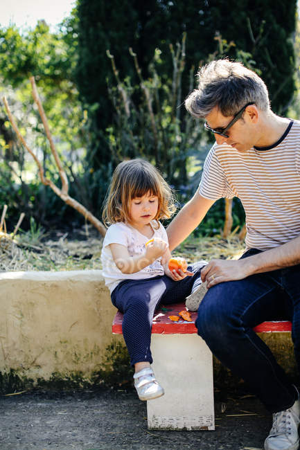 Отец и девочка наслаждаются апельсином — стоковое фото