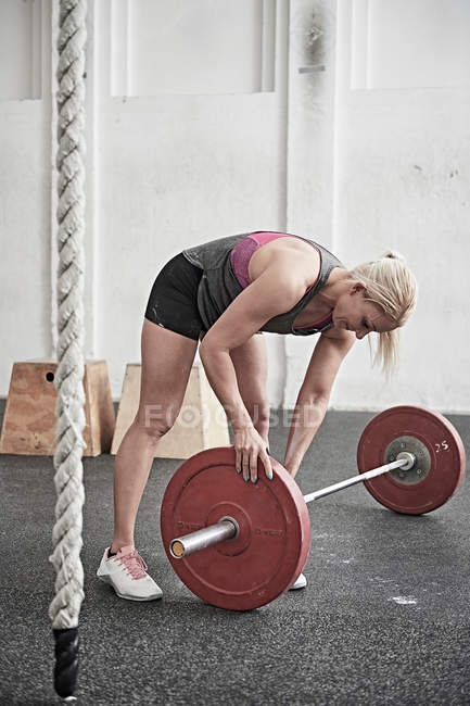 Woman adjusting barbell — Stock Photo