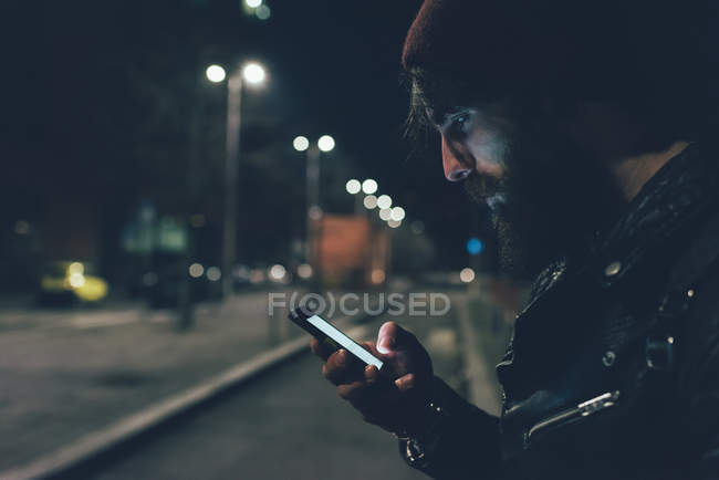 Hipster on city street looking at smartphone — Stock Photo